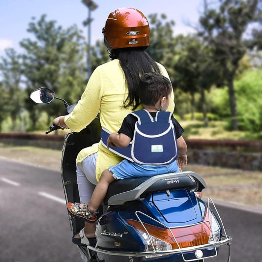 Mother and child riding scooty with navy blue baby safety belt harness providing secure support for toddler on 2-wheeler vehicle.